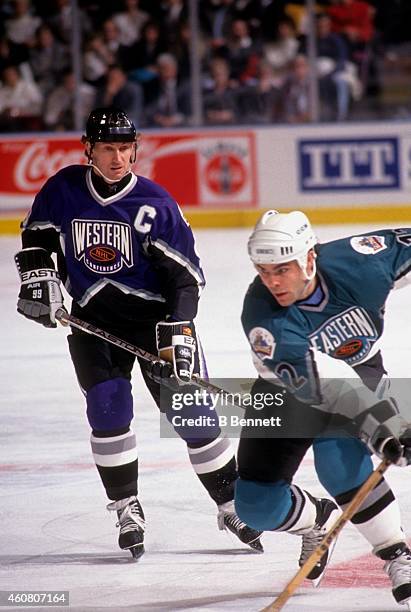 Wayne Gretzky of the Western Conference and the Los Angeles Kings watches Adam Oates of the Eastern Conference and the Boston Bruins skate with the...