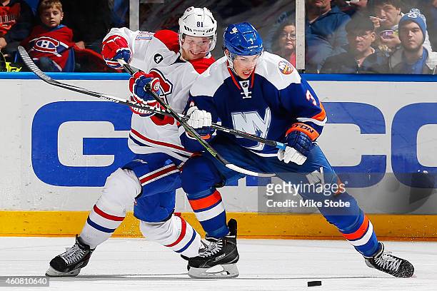 Lars Eller of the Montreal Canadiens battles for the puck with Travis Hamonic of the New York Islanders at Nassau Veterans Memorial Coliseum on...