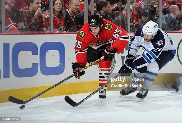 Andrew Shaw of the Chicago Blackhawks and Grant Clitsome of the Winnipeg Jets chase the puck during the NHL game at the United Center on December 23,...