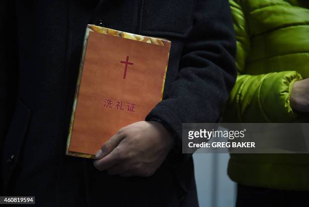 Man holds a certificate of baptism after he was baptised during a Christmas Eve service held by members of an underground church, at an apartment in...