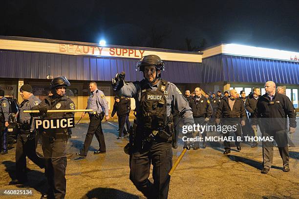 Police officers attempt to disperse demonstrators during a protest outside the Mobil On-The-Run gas and convenience store in Berkeley, Missouri on...