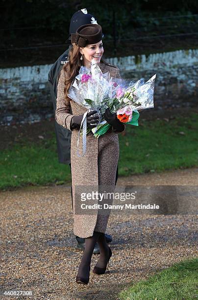 Catherine, Duchess of Cambridge carries bouquets of flowers as she attends a Christmas Day church service at Sandringham on December 25, 2014 in...