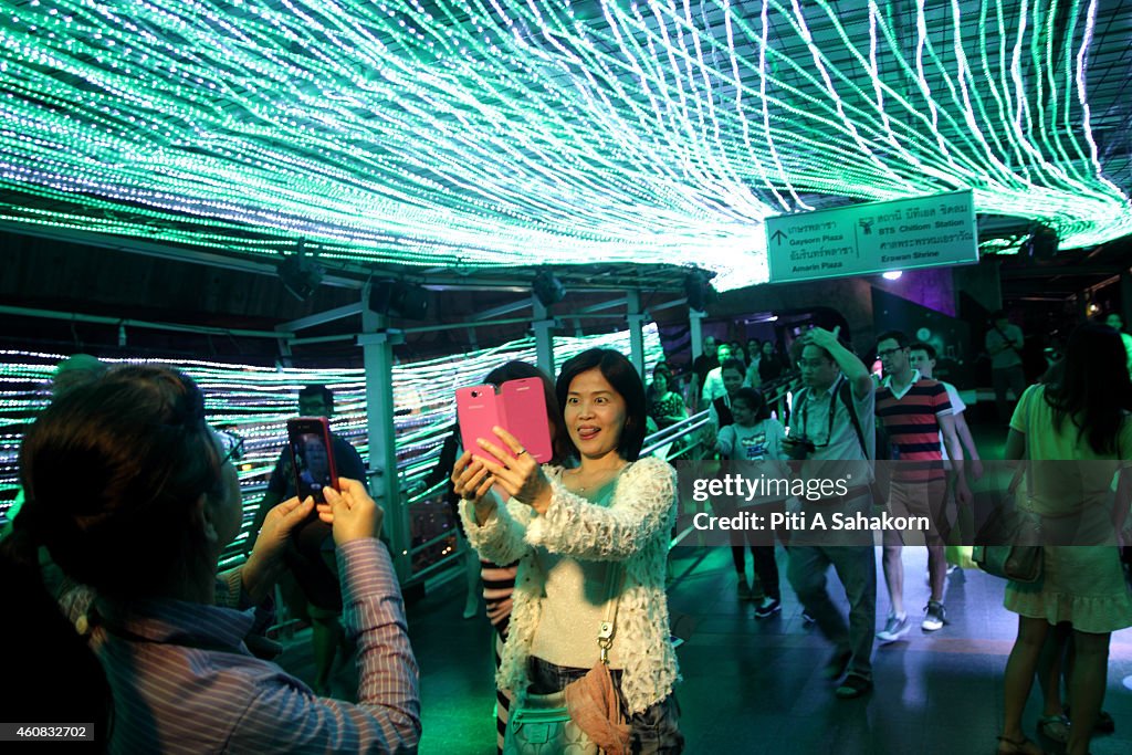 People take a selfie with a hanging lights display during...