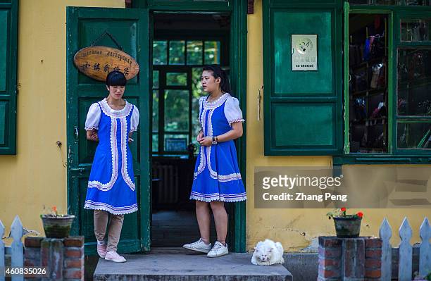 Wearing Russian styled skirts, two Chinese girls stand at the door of a traditional tailor shop. On the Sun Island, a famous scenic spot in Harbin,...