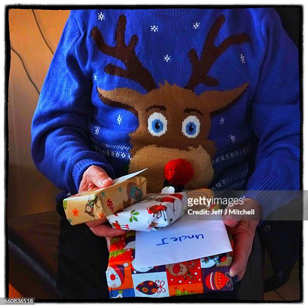 Man sports a Christmas jumper while opening Christmas present on December 25, 2014 in Glasgow, Scotland. Millions of people across the UK spend time...