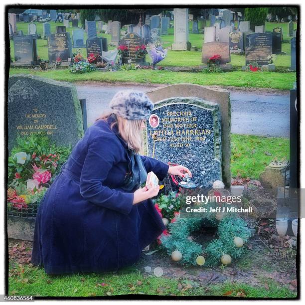 Woman lays a wreath at a relatives graveside on December 25, 2014 in Glasgow, Scotland. Millions of people across the UK spend time with family and...