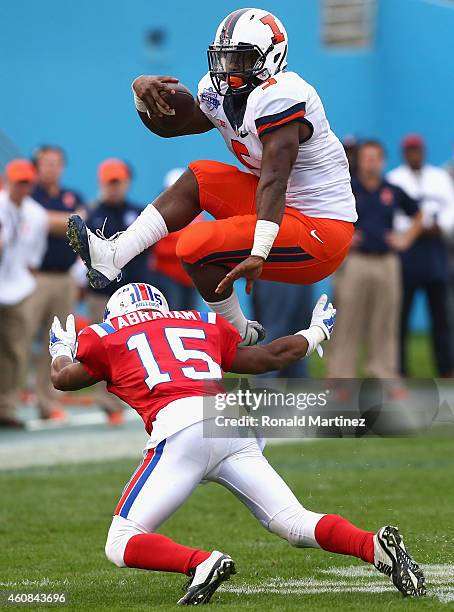 Donovonn Young of the Illinois Fighting Illini jumps over the tackle of Bryson Abraham of the Louisiana Tech Bulldogs during the Zaxby's Heart of...