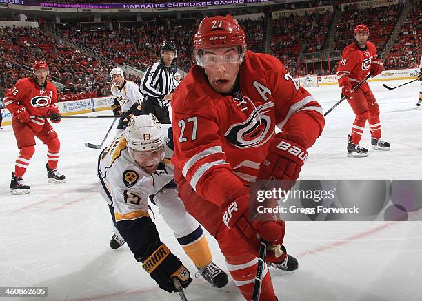 Justin Faulk of the Carolina Hurricanes and Nick Spaling of the Nashville Predators skate into the corner while battling for the puck during their...