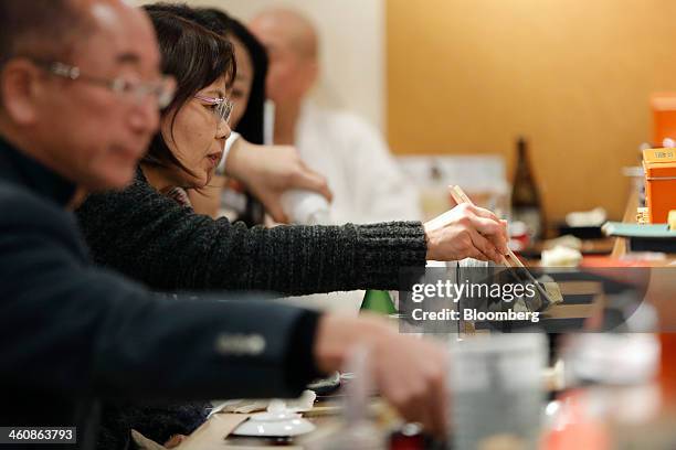 Customer picks up a piece of sushi with rolled egg using chopsticks at a Sushi Zanmai sushi restaurant, operated by Kiyomura K.K., in Tokyo, Japan,...