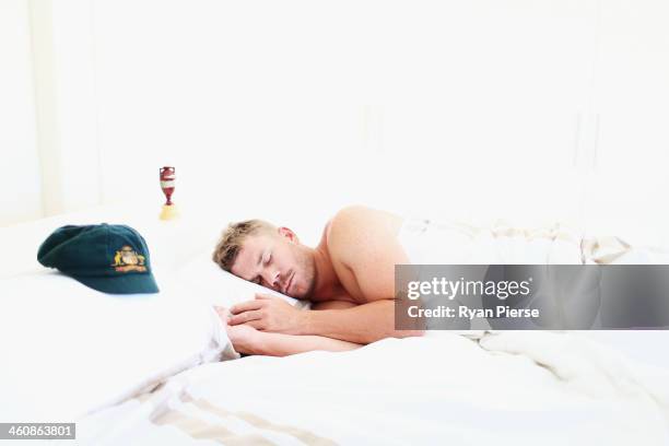 Australian Cricketer David Warner sleeps next to his Baggy Green Cap and a replica Ashes Urn at his home on January 6, 2014 in Sydney, Australia....