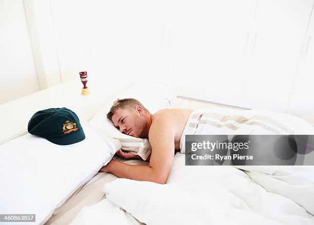 Australian Cricketer David Warner rests next to his Baggy Green Cap and a replica Ashes Urn at his home on January 6, 2014 in Sydney, Australia....