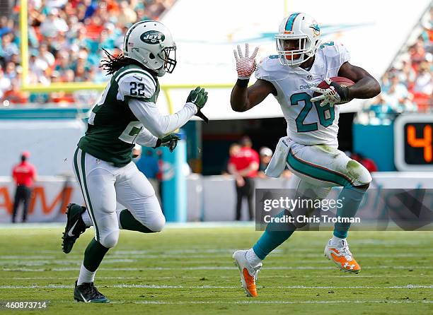 Running back Lamar Miller of the Miami Dolphins tries to elude cornerback Marcus Williams of the New York Jets in the second quarter during a game at...