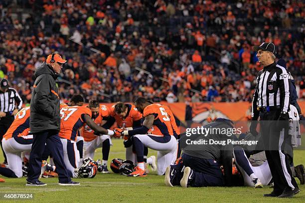 Head coach John Fox of the Denver Broncos walks the field and players bow their heads in prayer as strong safety David Bruton of the Denver Broncos...