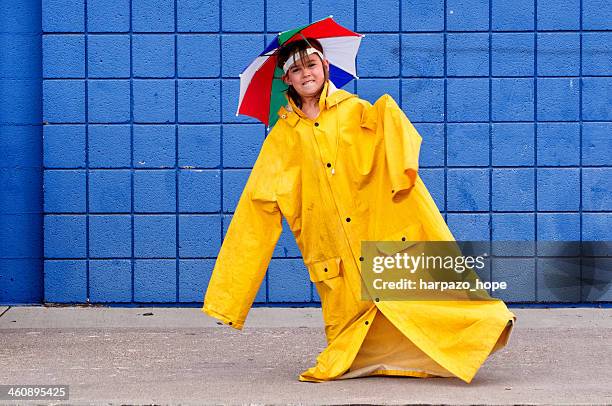 girl with over-sized raincoat and umbrella hat. - レインコート ストックフォトと画像