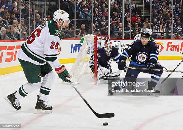 Thomas Vanek of the Minnesota Wild plays the puck to the side of the net as goaltender Michael Hutchinson and Grant Clitsome of the Winnipeg Jets...