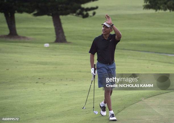President Barack Obama waves to onlookers as he plays golf at the Mid-Pacific Country Club in Kailua on December 29, 2014 . AFP PHOTO/NICHOLAS KAMM