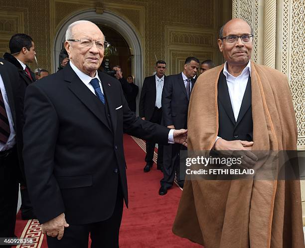 Tunisian newly-elected President Beji Caid Essebsi stands next to his predecessor Moncef Marzouki during a handover ceremony on December 31, 2014 at...