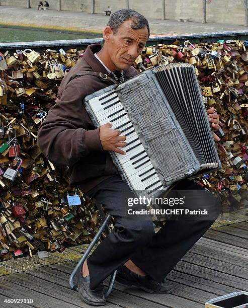 Paris and the Seine, accordionist playing on the Pont des Art decorated with many padlocks hung by lovers on June 17, 2014.