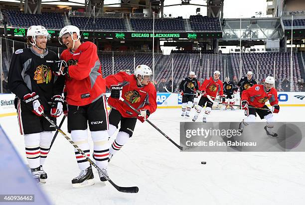 Duncan Keith and Marian Hossa of the Chicago Blackhawks share a laugh as teammates Patrick Kane and Patrick Sharp skate with the puck during practice...