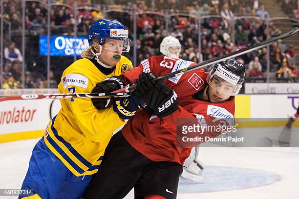 Forward Julius Bergman of Sweden battles against forward Luca Hischier of Switzerland during the 2015 IIHF World Junior Championship on December 31,...