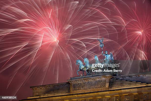 Fireworks explode behind the Quadriga statue on top of the Brandenburg Gate shortly after midnight on January 1, 2015 in Berlin, Germany. Tens of...