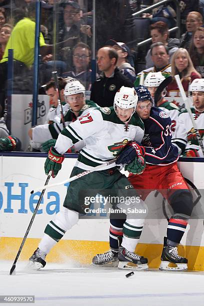 Brett Sutter of the Minnesota Wild and Michael Chaput of the Columbus Blue Jackets battle for a loose puck during the first period on December 31,...