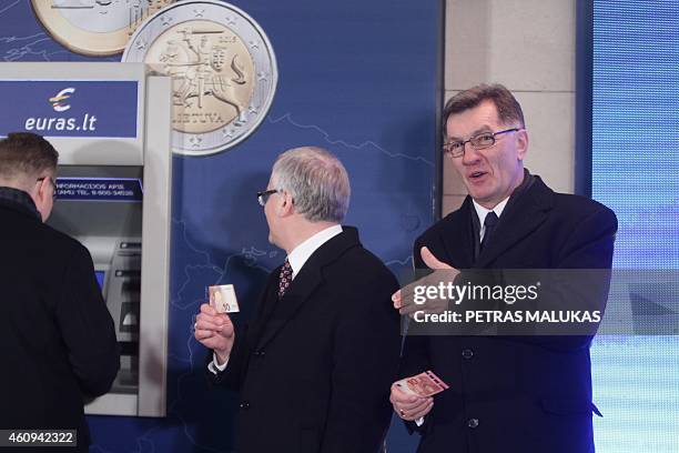 Lithuania Finance Minister Rimantas Sadzus and Lithuanian Prime Minister Algirdas Butkevicius symbolically withdraw euros from a bank machine during...