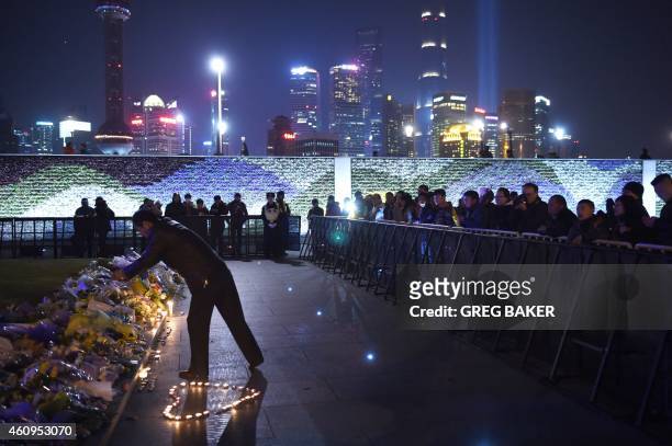 Man places flowers at the site of a New Year's Eve stampede at The Bund in Shanghai on January 1, 2015. The New Year's stampede on Shanghai's...