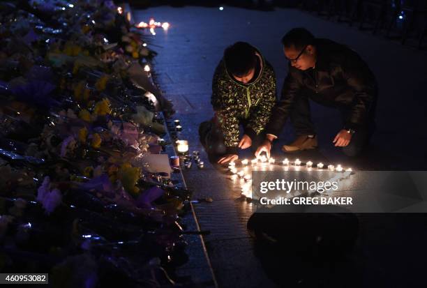 Two men place candles in the shape of a heart at the site of a New Year's Eve stampede at The Bund in Shanghai on January 1, 2015. The New Year's...