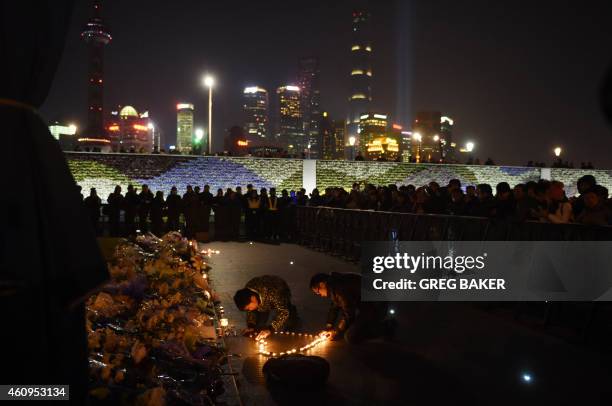 Two men place candles in the shape of a heart at the site of a New Year's Eve stampede at The Bund in Shanghai on January 1, 2015. The New Year's...