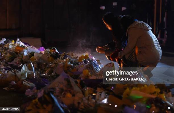 Two women place candles at the site of a New Year's Eve stampede at The Bund in Shanghai on January 1, 2015. The New Year's stampede on Shanghai's...