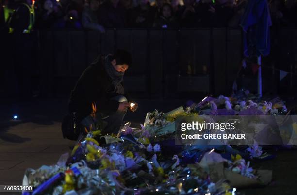 Man places a candle at the site of a New Year's Eve stampede at The Bund in Shanghai on January 1, 2015. The New Year's stampede on Shanghai's...