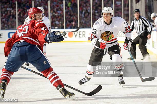 Mike Green of the Washington Capitals reaches for the puck next to Kris Versteeg of the Chicago Blackhawks during the 2015 Bridgestone NHL Winter...
