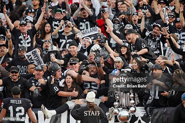 Linebacker Sio Moore of the Oakland Raiders jumps into arms of fans in the Black Hole after defeating the San Francisco 49ers on December 7, 2014 at...