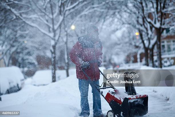 Larry Thomas snow blows several inches of snow from a sidewalk as the area deals with record breaking freezing weather January 6, 2014 in Detroit,...