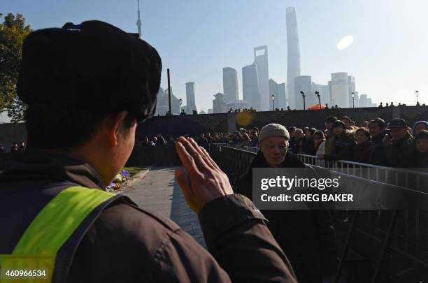 Security guard salutes an elderly man who placed flowers at the site of a New Year's Eve stampede at the Bund in Shanghai on January 2, 2015. The New...