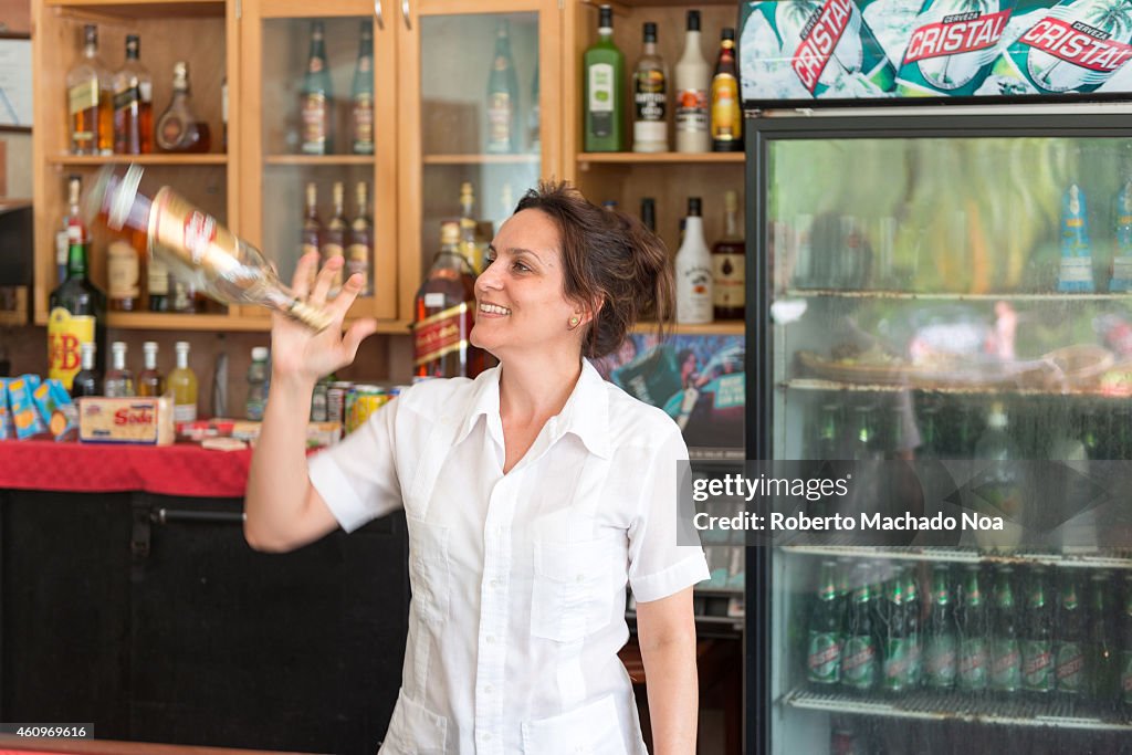 Cuban female bartender in tourist hotel and juggling with...