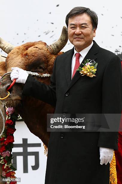 Shin Je Yoon, chairman of South Korea's Financial Services Commission, poses for a photograph with a bull during a ceremony marking the first day of...