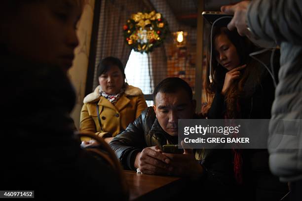 Relatives of victims of a New Year's Eve stampede watch news reports about the incident on a mobile phone in Shanghai on January 2, 2015. The New...