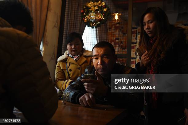 Relatives of victims of a New Year's Eve stampede watch news reports about the incident on a mobile phone in Shanghai on January 2, 2015. The New...