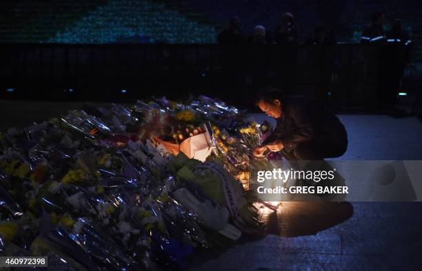 Man lights candles near flowers at the site of the New Year's Eve stampede in Shanghai on January 2, 2015. The New Year's stampede just before...