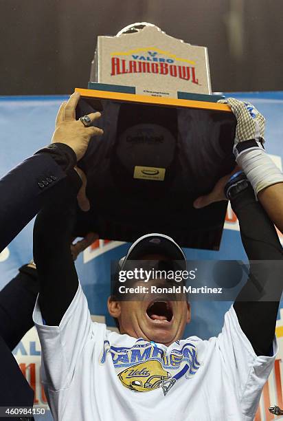Head coach Jim Mora of the UCLA Bruins lifts the Alamo Bowl trophy after a 40-35 win against the Kansas State Wildcats during the Valero Alamo Bowl...