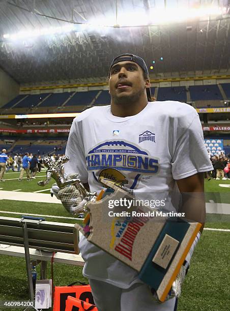 Eric Kendricks of the UCLA Bruins walks off the field with the defensive player of the game trophy during the Valero Alamo Bowl at Alamodome on...