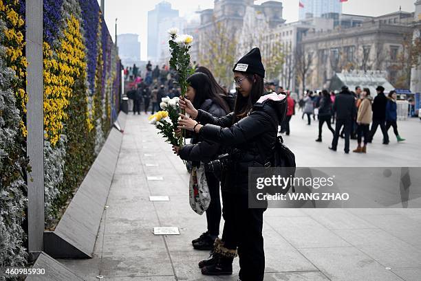 Group of women pray with flowers at the site of the New Year's Eve stampede in Shanghai on January 3, 2015. The New Year's stampede just before...