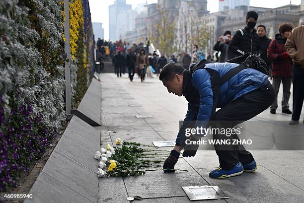 Man places flowers as he prays for the victims at the site of the New Year's Eve stampede in Shanghai on January 3, 2015. The New Year's stampede...