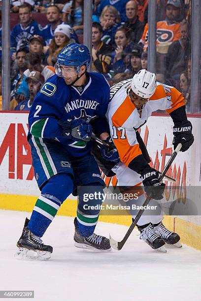 Dan Hamhuis of the Vancouver Canucks checks Wayne Simmonds of the Philadelphia Flyers into the boards on December 30, 2013 at Rogers Arena in...