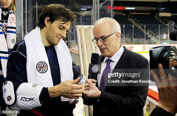 Ben Chiarot of the Winnipeg Jets is presented the game puck by Hockey Night In Canada reporter Scott Oake after scoring his first NHL goal against...