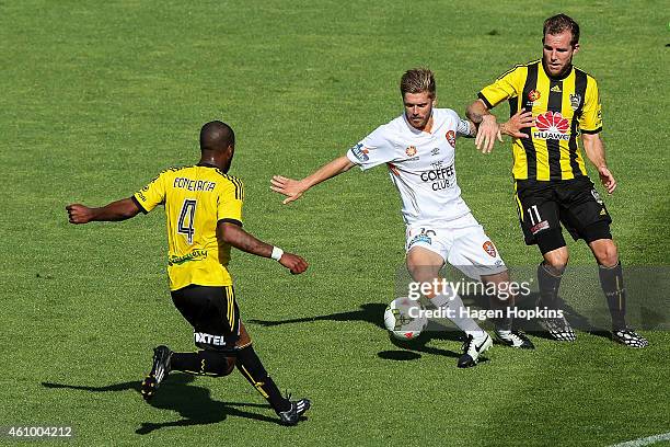 Luke Brattan of the Roar looks to beat Roly Bonevacia and Jeremy Brockie of the Phoenix during the round 15 A-League match between the Wellington...