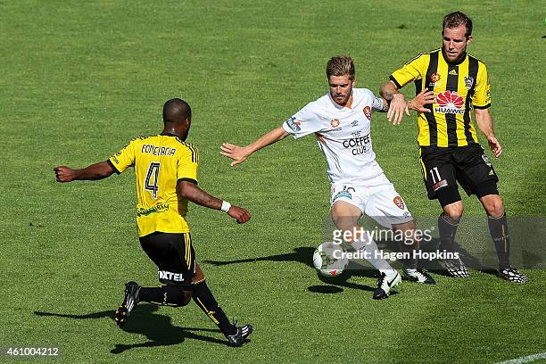 Luke Brattan of the Roar looks to beat Roly Bonevacia and Jeremy Brockie of the Phoenix during the round 15 A-League match between the Wellington...