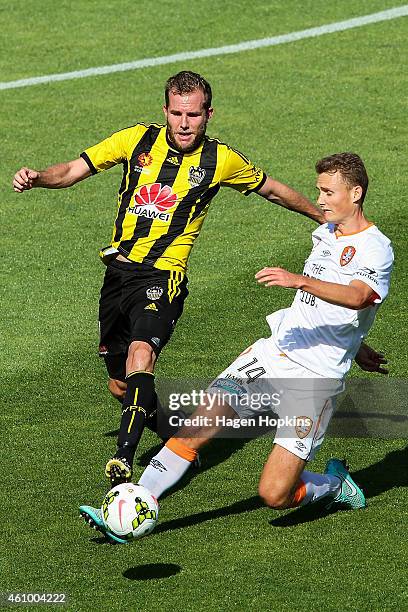 Daniel Bowles of the Roar clears the ball under pressure from Jeremy Brockie of the Phoenix during the round 15 A-League match between the Wellington...